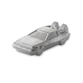 OUTATIME. A shimmering, silver bath bomb shaped like a futuristic, angular car reminiscent of a DeLorean from the nostalgic nineties films, "Back To The Future". The product has a metallic glint, and the car features detailed windows and rear fins.
