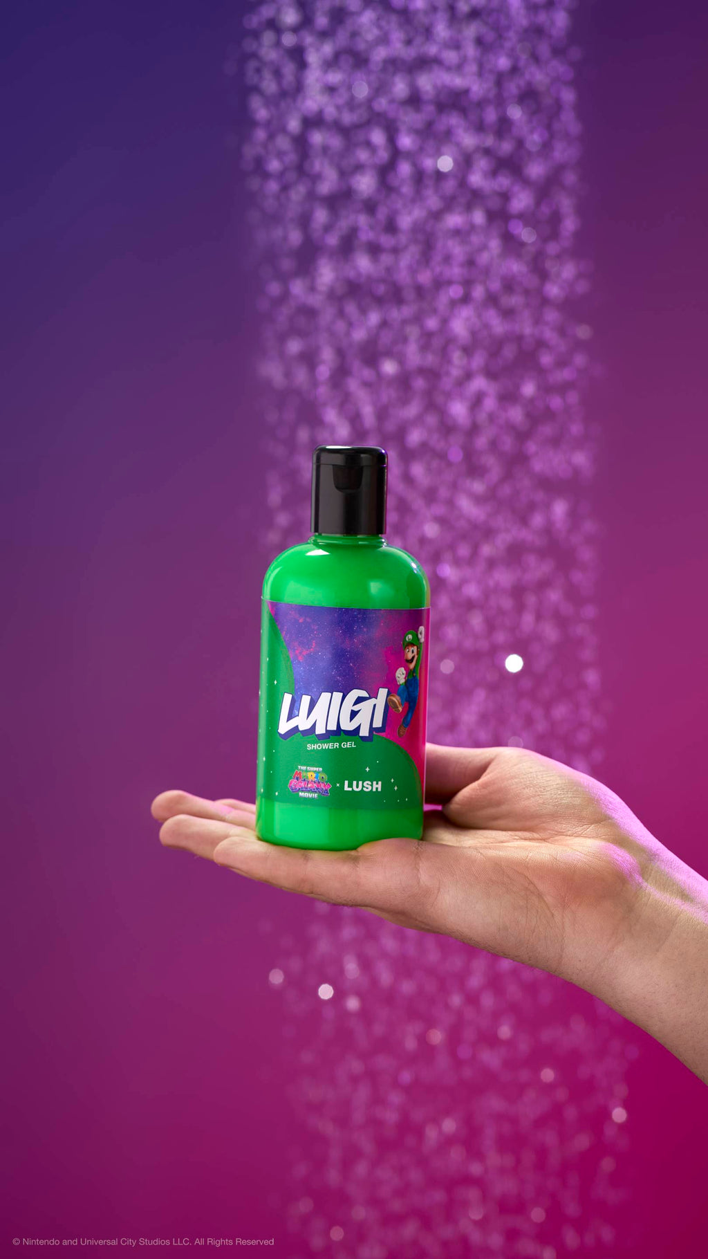 Hand holds a green Luigi shower gel bottle against a purple background with blurred water. Label features Luigi in space with movie and LUSH logos.