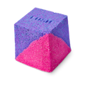 A cube-shaped Deep sleep Salt Cube bath bomb split diagonally into vibrant purple and neon pink. The purple top surface features the embossed "LUSH" logo.