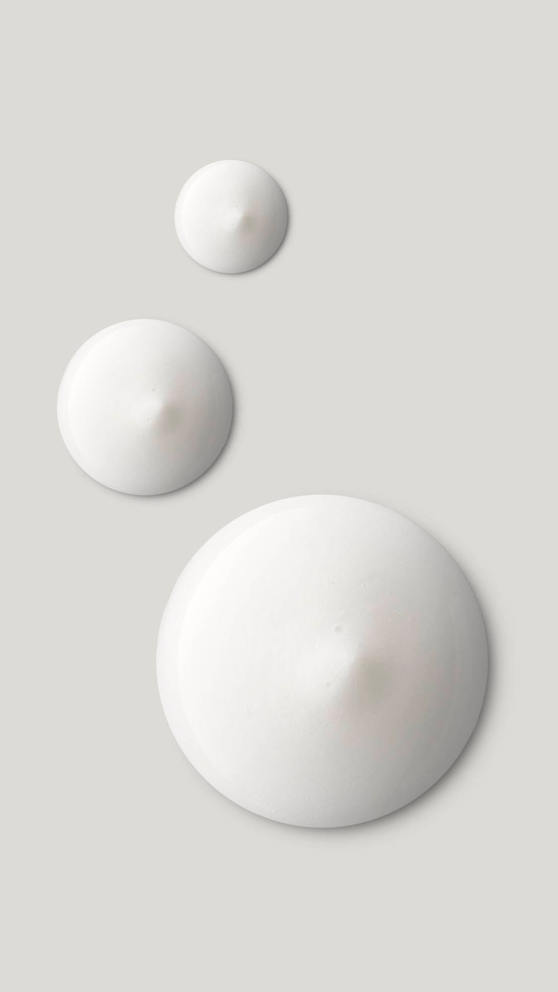 The image shows three circular product droplets getting larger. They are perfect circular swatches of bright white Enchanted eye cream.