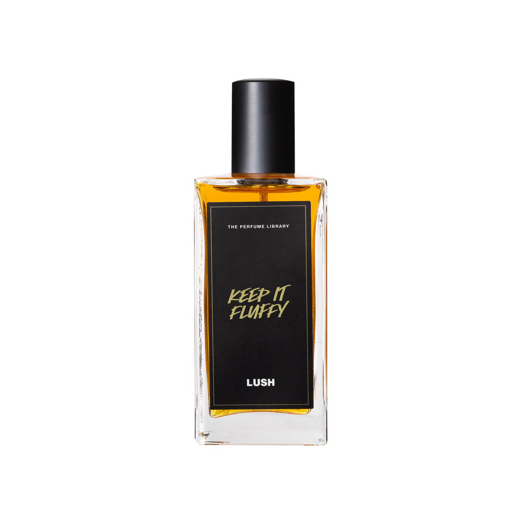 A glass perfume bottle filled with dark amber liquid. A black label reads 'The Perfume Library' and 'Keep It Fluffy'.