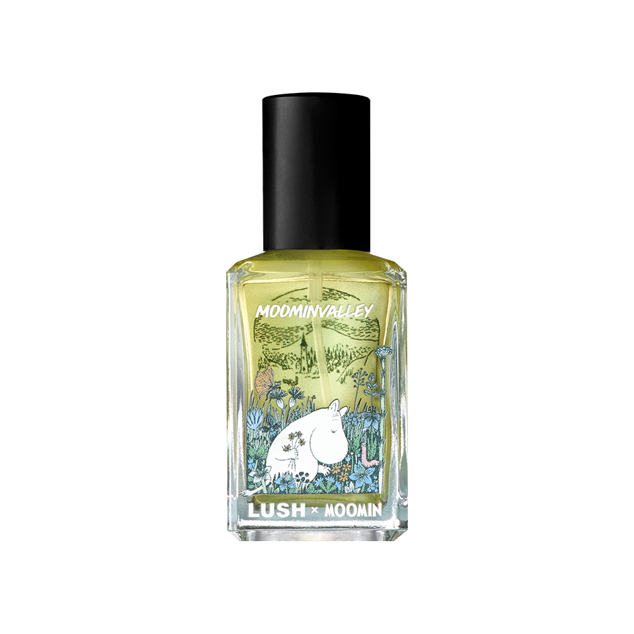 A rectangular glass bottle of pale perfume with a black cap. The clear, illustrated label reads "MOOMINVALLEY" and "LUSH x MOOMIN", featuring an illustration of Moomintroll holding flowers in a grassy field.