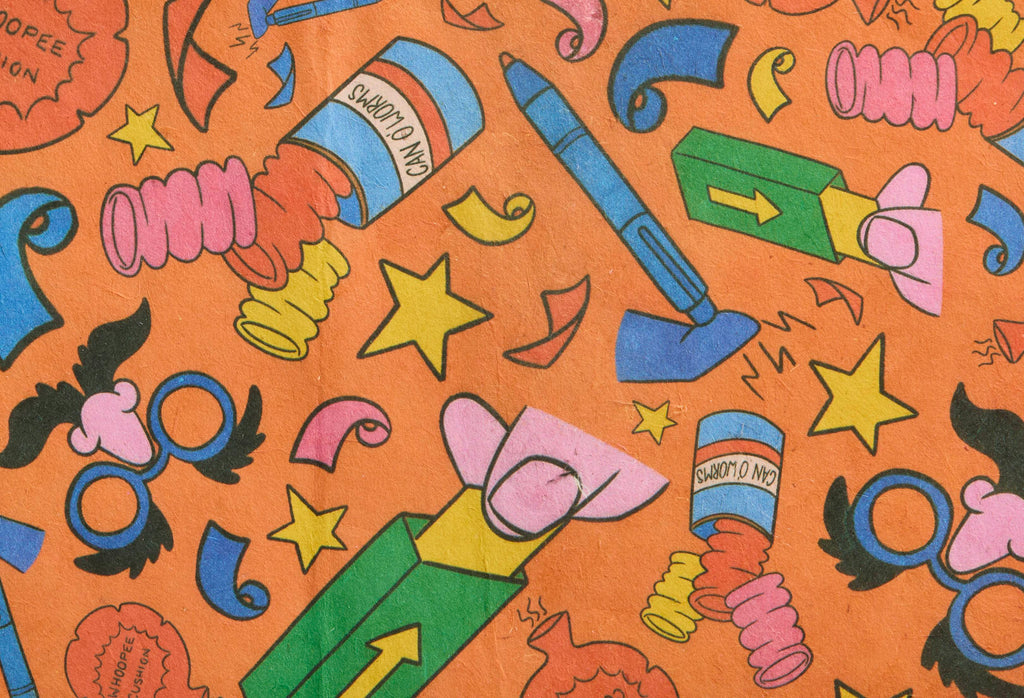 Practical Joker. A rectangular sheet of thick, gift-wrapping paper. The design is a bright orange background with lined, colourful illustrations of accessories associated with impractical jokes such as false gum, can of worms and whoopee cushions.