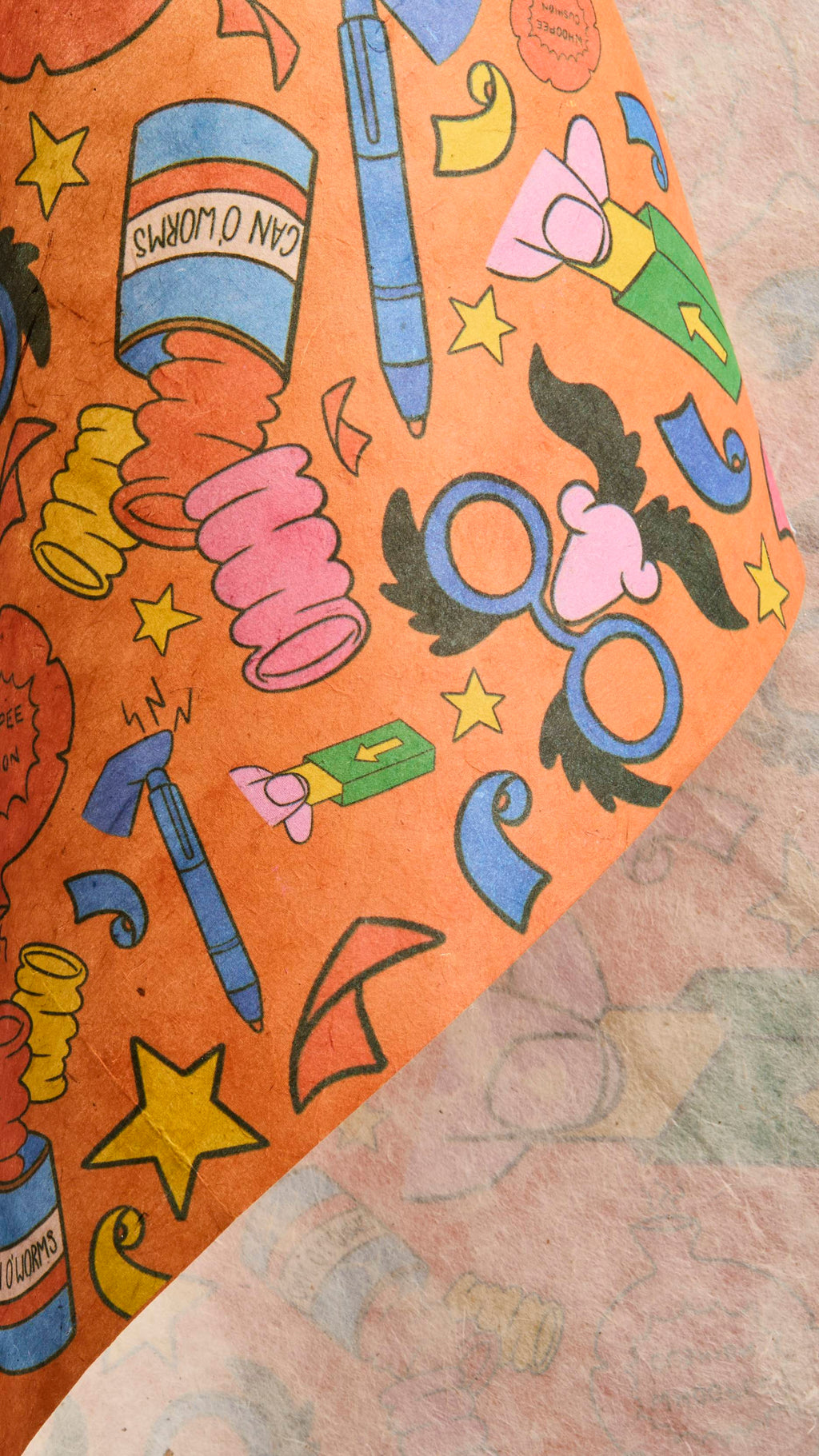 The image shows the thick, colourful sheet of orange Practical Joker lokta paper being gently rolled over itself to reveal its whitened, textured underside.