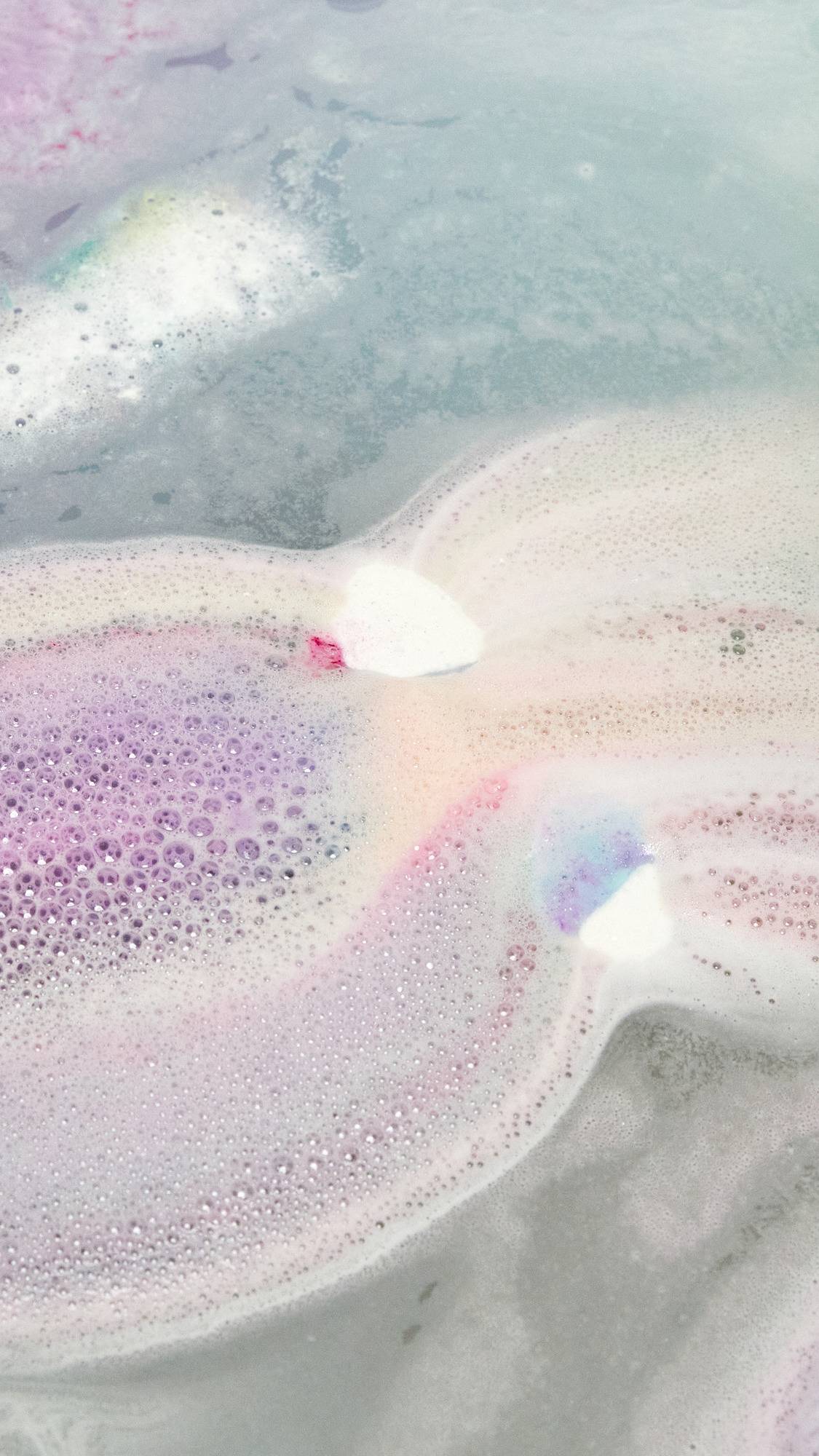 The Somewhere bath bomb is slowly dissolving leaving behind delicate, pink and blue pastel waters with thin velvety foam.