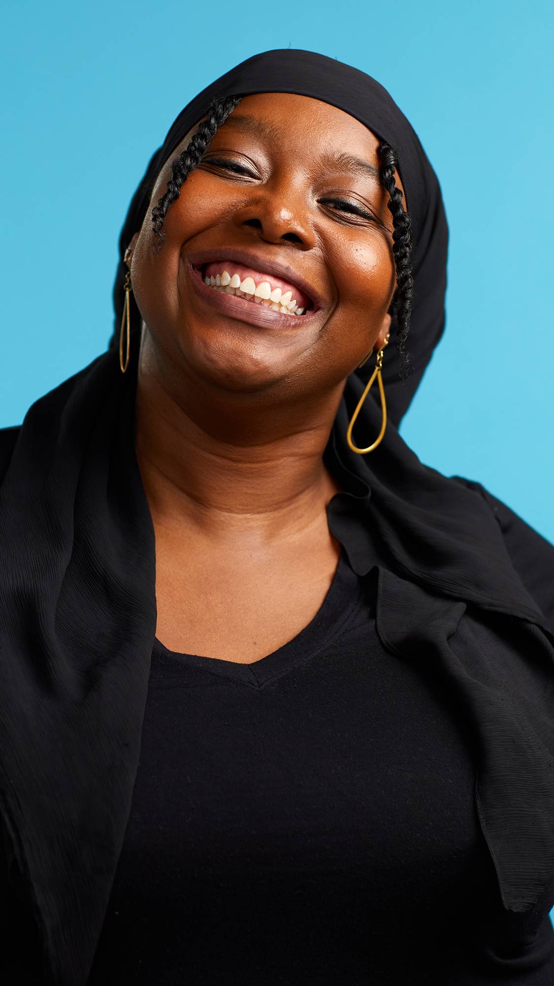 The image shows the model on a sky-blue background wearing a back top. They have just brushed their teeth with the Soother toothpaste and are smiling at the camera with gleaming, shiny, fresh teeth.