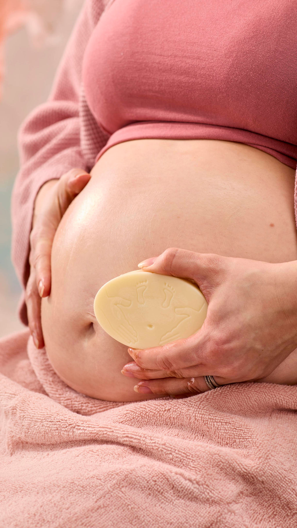 A close-up shot of the model's pregnant belly as they smooth over the moisturising The Bump solid massage bar over this skin.