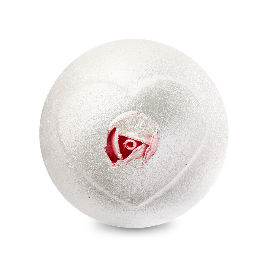 A top-down view of the Wedding bath bomb depicts a shimmering, pearlescent white sphere against a solid black background. An embossed heart shape on the surface reveals a realistic pink rosebud inside its center.